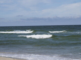 Waves on the sea coast under a blue sky with clouds