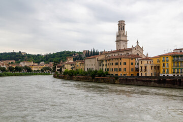 Fototapeta premium a panoramic view over the famous river called Etsch at cloudy day in Verona, italy. With the beautiful city scape of historic architecture buildings