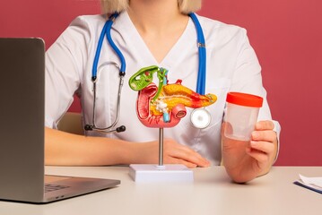 woman doctor hand hold test tube sits in her office with anatomical model pancreas on desk