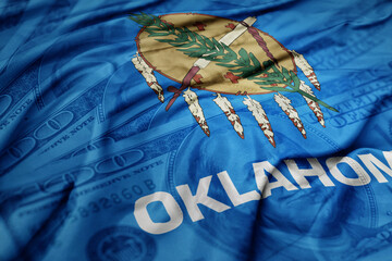 waving colorful oklahoma state flag on the dollar money background. finance concept.