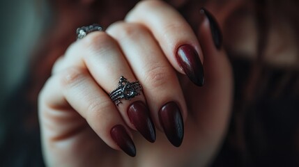 A graceful hand adorned with dark red gothic nail art, featuring a distinctive ring, expressing a sense of elegance, mystery, and intricate design artistry.