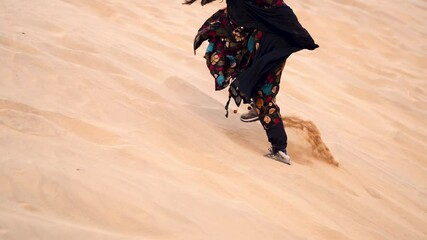 Close up shot of Indian woman climbing on sand dune and struggling to walk in desert sand. Tourist in Thar desert of Jaisalmer during desert safari. 