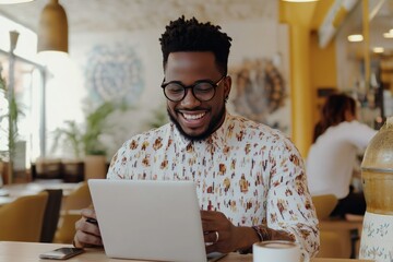 Happy man using laptop in modern café setting