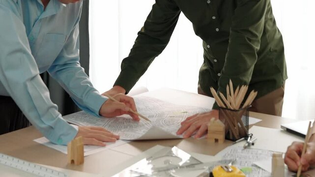 Professional engineer measuring the blueprint. Professional engineer working architectural project at studio on a table with yellow helmet and architectural equipment scatter around. Delineation.