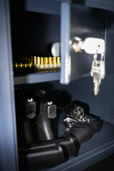 Firearms. Modern pistols, revolver and ammo in a gun safe, close up vertical photo.