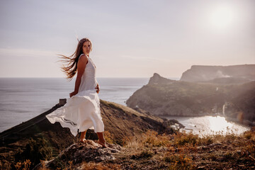 A woman stands on a hill overlooking the ocean. She is wearing a white dress and has long hair. The scene is serene and peaceful, with the sun shining brightly in the background.