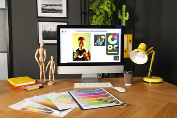 Naklejka premium Designer's workplace with computer, stationery and palettes on wooden table indoors