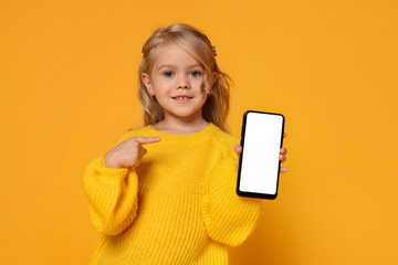 Fototapeta premium Cute little girl with smartphone against orange background