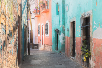 Fototapeta premium A narrow cobblestone alleyway in Guanajuato, Mexico lined with vibrant pastel walls and traditional Spanish colonial architecture.