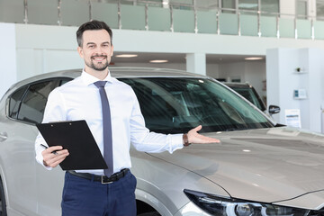 Happy salesman near new silver car in salon