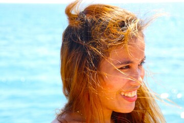 beautiful female model laughing and smiling with blue sky and beach behind her