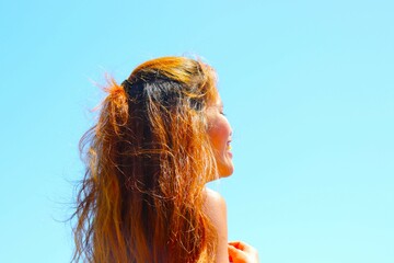 beautiful female model laughing and smiling with blue sky and beach behind her