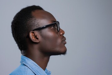 Obraz premium African man in blue shirt and glasses profile view.