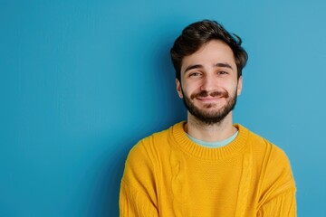 Fototapeta premium Man in yellow sweater smiling in photo on blue background.