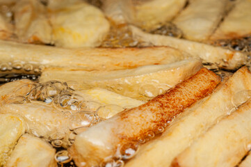 Potato fries sizzle and bubble in hot oil, becoming crispy and golden