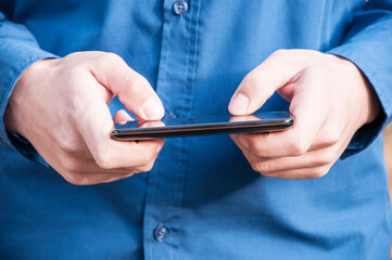 Texting sms. Close up view of male hands typing text message outdoors