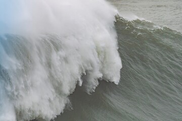 A colossal wave crashing with immense power and spray in Nazare, Portugal