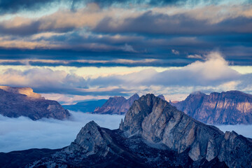 Fototapeta premium Mountains above the clouds stunning landscape. High rocky peaks rising through mist, this scene captures dramatic high-altitude views with soft cloud cover and rugged terrain in Dolomiti Alps