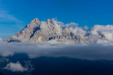 Obraz premium Mountains above the clouds stunning landscape. High rocky peaks rising through mist, this scene captures dramatic high-altitude views with soft cloud cover and rugged terrain in Dolomiti Alps