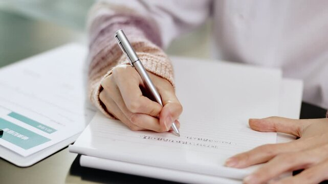 School, class and hands of student writing on paper for assignment, examination and assessment. Education, university test and person with notes for studying, learning and lesson in Japanese college