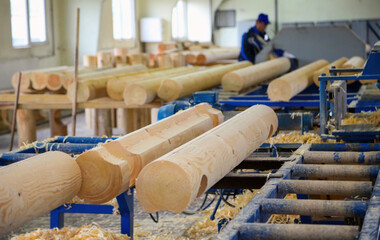 Craftsman shaping wooden logs at carpentry workshop with machinery in use during daylight hours