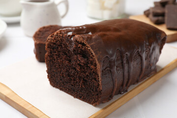 Delicious chocolate sponge cake on white tiled table, closeup