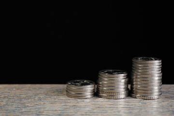 Stacked coins on wooden table against black background, closeup with space for text. Salary concept