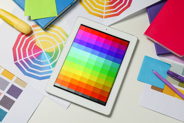 Designer's workplace with tablet, different palettes and stationery on white table, flat lay