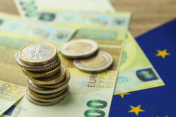 Euro banknotes, coins and European Union flag on table, closeup