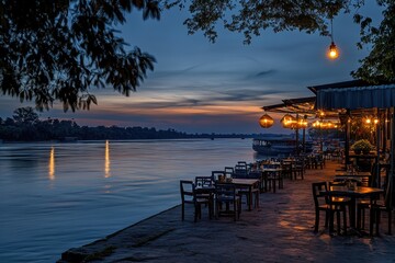 Obraz premium A tranquil river scene with outdoor seating area featuring tables and chairs