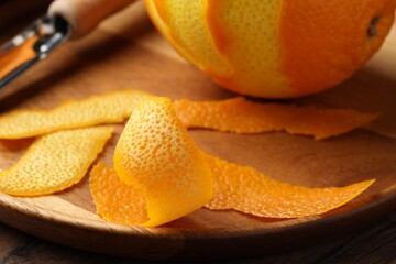 Fresh orange peel and fruit on wooden table, closeup