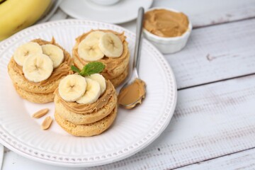 Tasty sandwiches with peanut butter, banana, mint and spoon on white wooden table, closeup