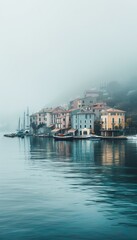 Fototapeta premium Serene Coastal Town in Morning Fog with Boats and Buildings for Atmospheric Decor or Print