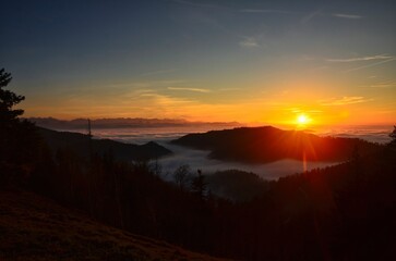 Sunset over the sea of ​​fog on the Schnebelhorn hill in the canton of Zurich. Beautiful evening atmosphere in the Zürich Oberland above the fog. High quality photo.