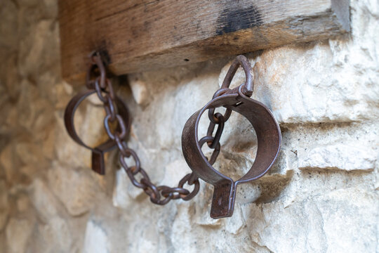 Old medieval patinaed handcuffs on the stone wall