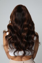 Naklejka premium Beautiful young woman with luxurious curly long hair. Back view. Vertical.