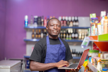 A cheerful shopkeeper stands in a grocery store, confidently using a laptop. The background shows shelves filled with products, showcasing a vibrant and modern retail environment.