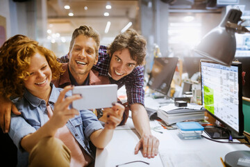 Young group of people taking a selfie while working in the office together