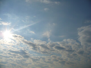 Sunny blue sky with sun rays and Stratocumulus clouds - natural background. Topics: pattern, weather, meteorology, sun energy, season, beauty of nature, air space