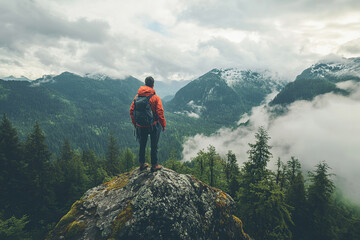 Adventurer observing mountain landscape surrounded by misty clouds, outdoor activities, hiking