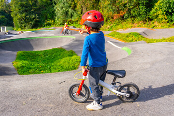 A young boy in a red helmet rides a bicycle on a paved surface
