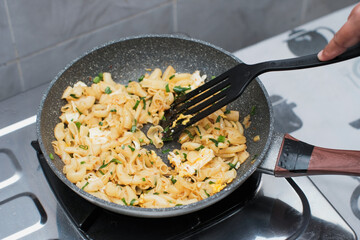 A closeup of a women hand cooking the macaroni or penne pasta in wok pan, cooking pasta homemade.