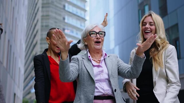 Animated female group of diverse urban professionals outside office building enjoy funny dancing celebrating job promotion. Excited team of only business women partners having fun together outdoors