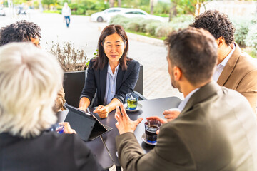 Chinese businesswoman talking with colleagues using tablet in a cafeteria