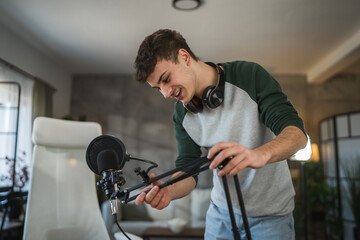 man blogger stand and prepare microphone for new video at home studio