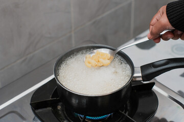 A women cooking the pasta macaroni or penne pasta in wok pan pot in boiling water, cooking pasta homemade.