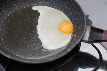 Fried egg. Close up view of the fried egg on a frying pan on gas stove, cooking egg homemade.