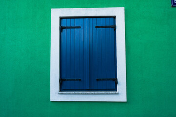 Blue window shutters on green wall - background wallpaper