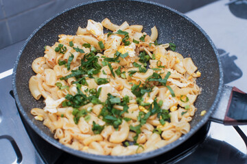 A closeup of a cooking the pasta macaroni or penne pasta with spring onions and celery in pan,  cooking pasta homemade.