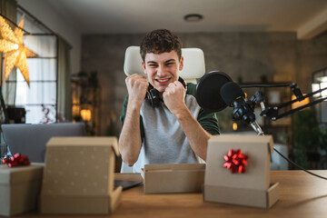 Young man open gift while record a podcast or stream at home studio